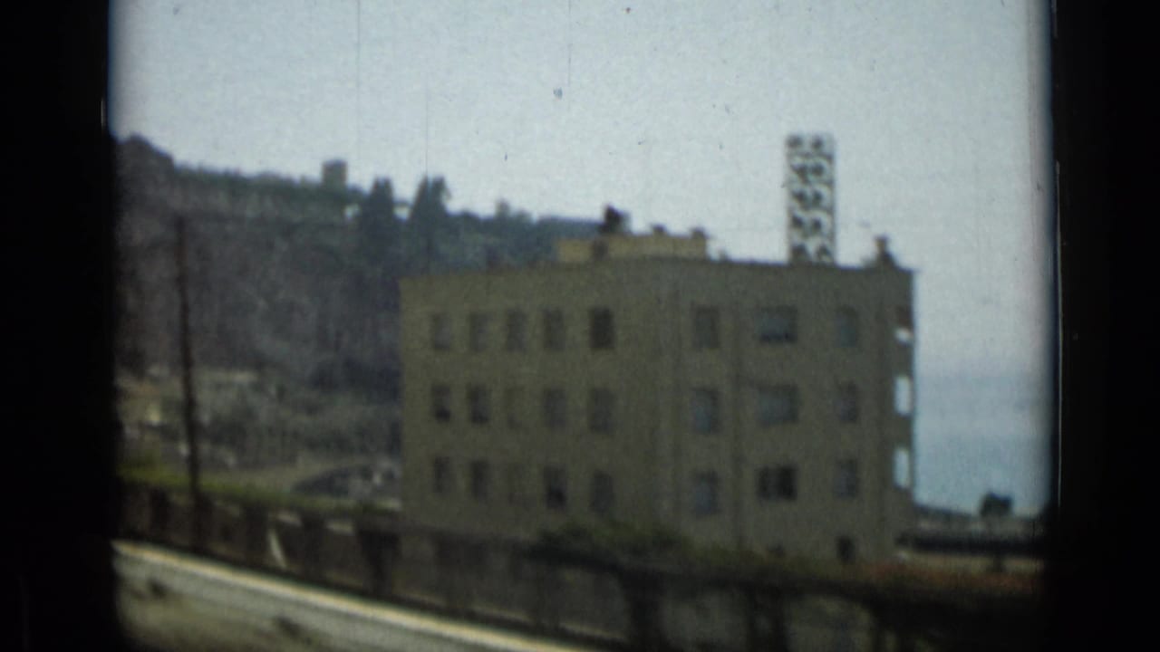 Multi-story building beside a coastal road with cliff and sea beyond.
