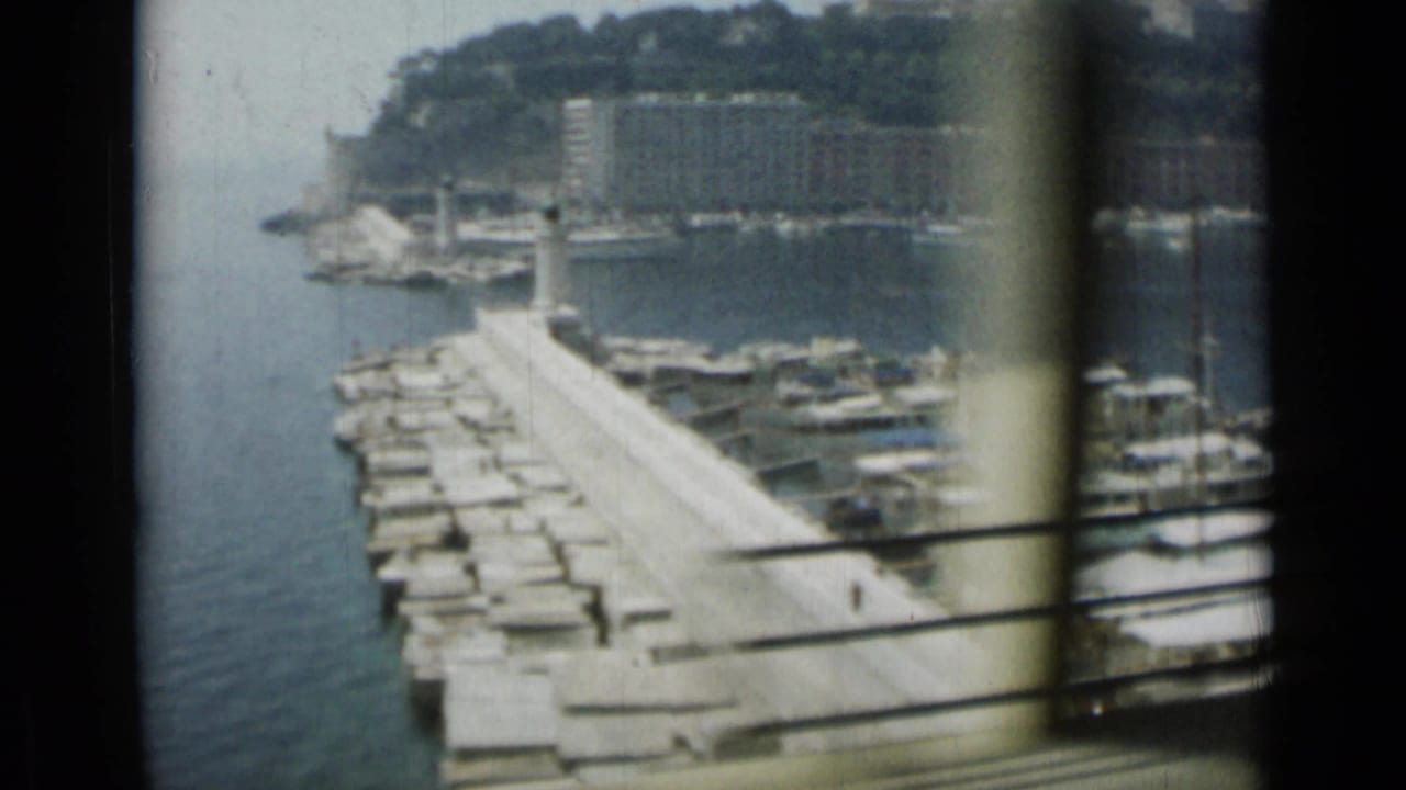 Harbor pier with small boats seen through a dark window frame.