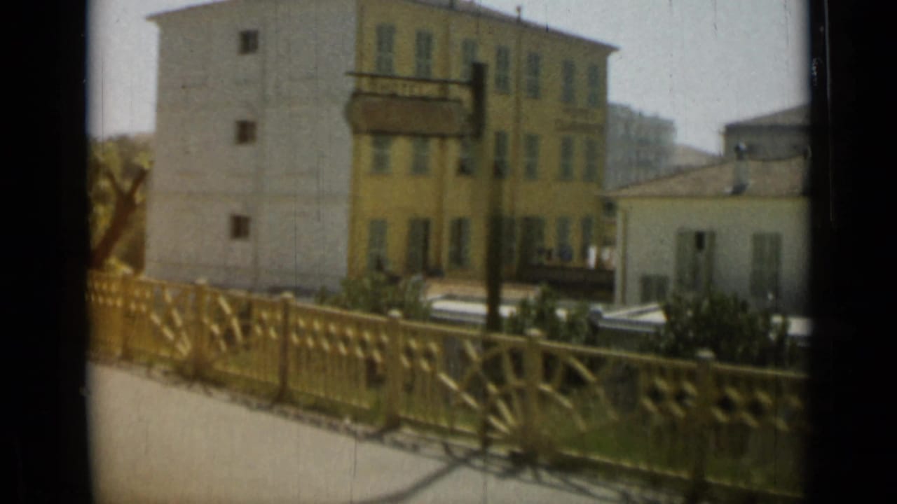 Decorative railing in front of pale buildings and a yellow multi-story facade.