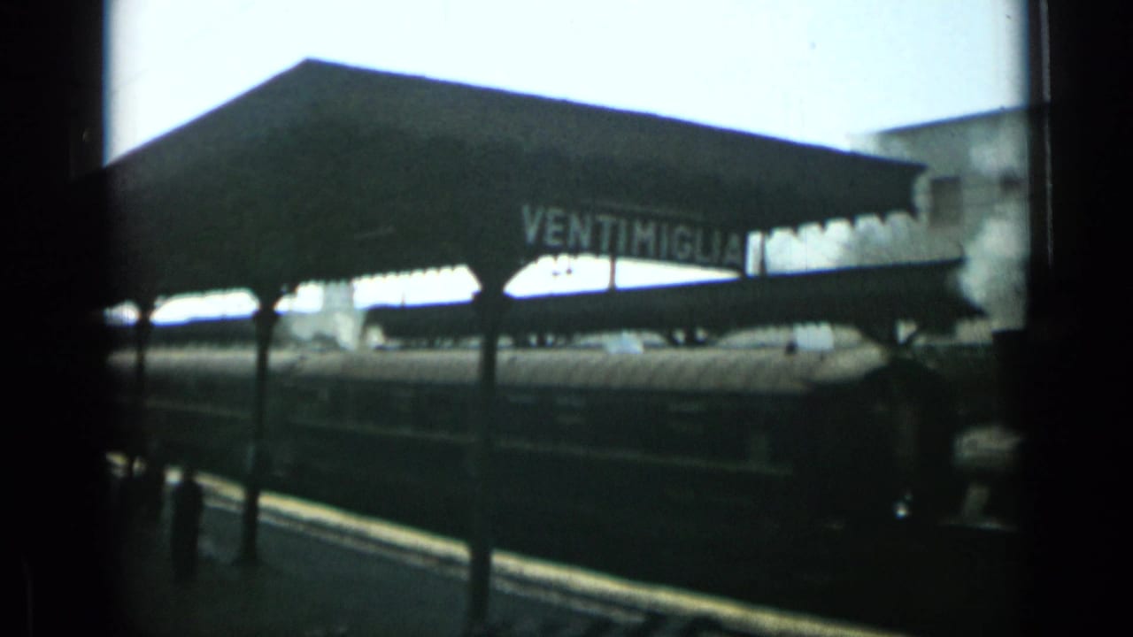 Ventimiglia station canopy beside a passenger train on a platform.