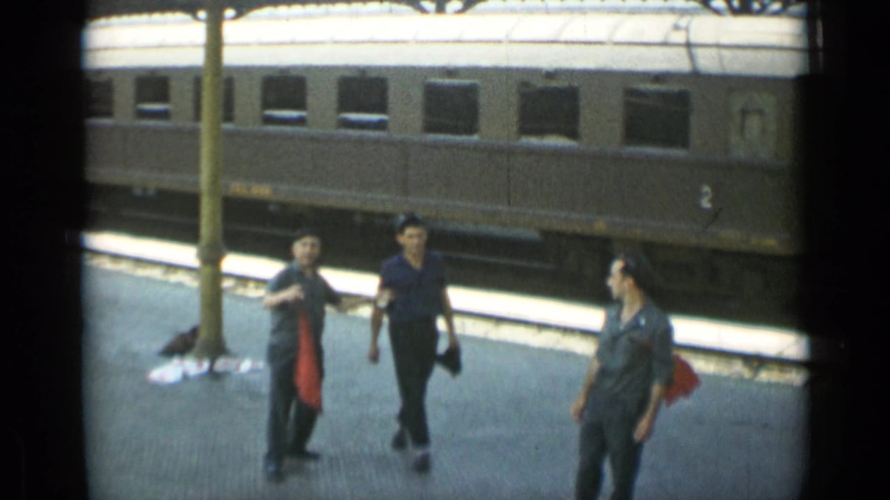 Three young men walk on a station platform beside a passenger rail car.
