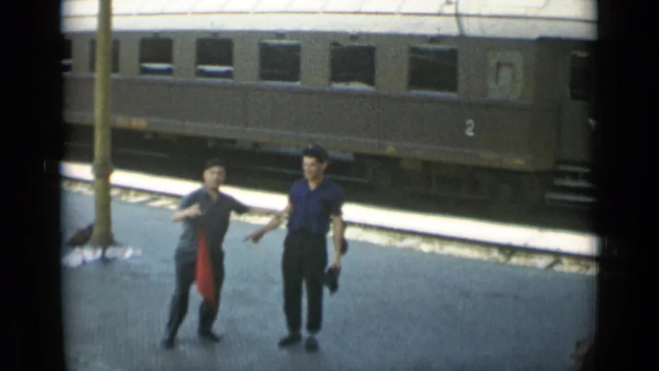 Near the end of the 1962 home-movie shot, two men remain centered on the platform with the train car behind them.