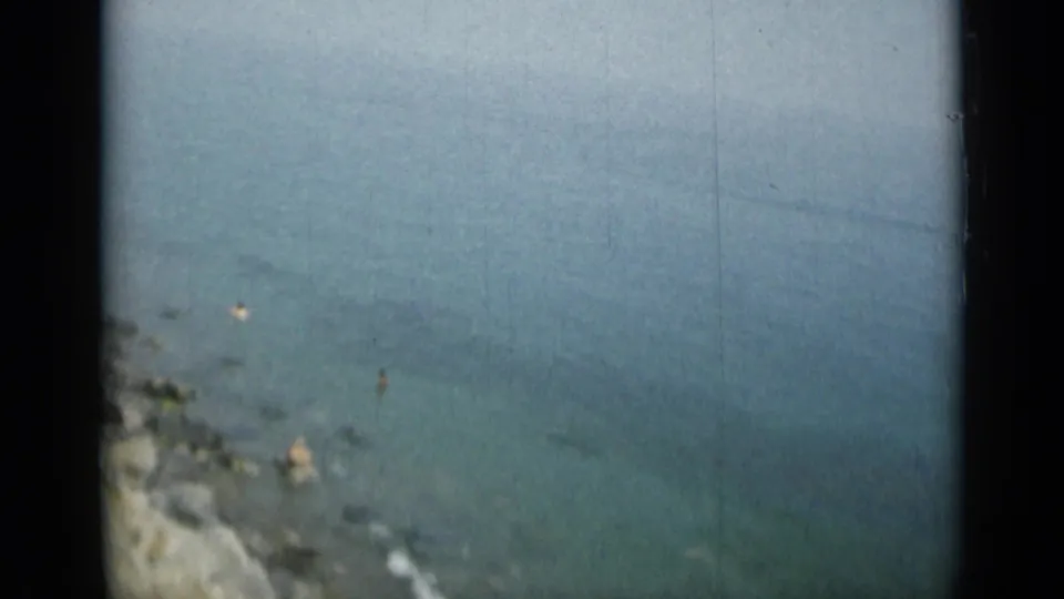 1962 8mm view of swimmers near rocks in clear coastal water, likely from Monaco or nearby Italian shoreline.