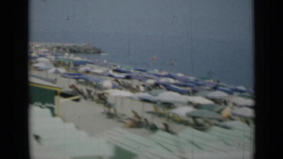 1962 Monaco beach view with dense rows of umbrellas, deck chairs and the Mediterranean water beyond.