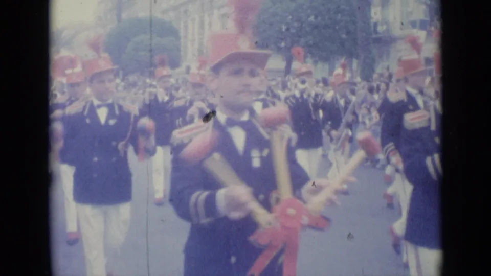 Close 1962 Nice parade view of a uniformed band member in a red hat carrying red-tipped percussion or baton-like items.