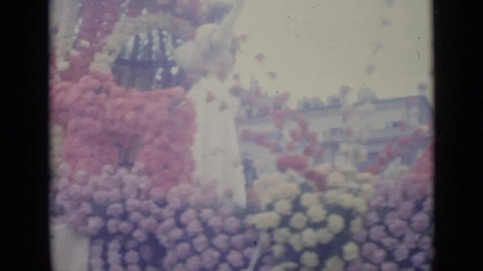 The final frame shows the woman on the flower float in 1962 Nice, with spectators and low urban buildings visible beyond the floral decorations.
