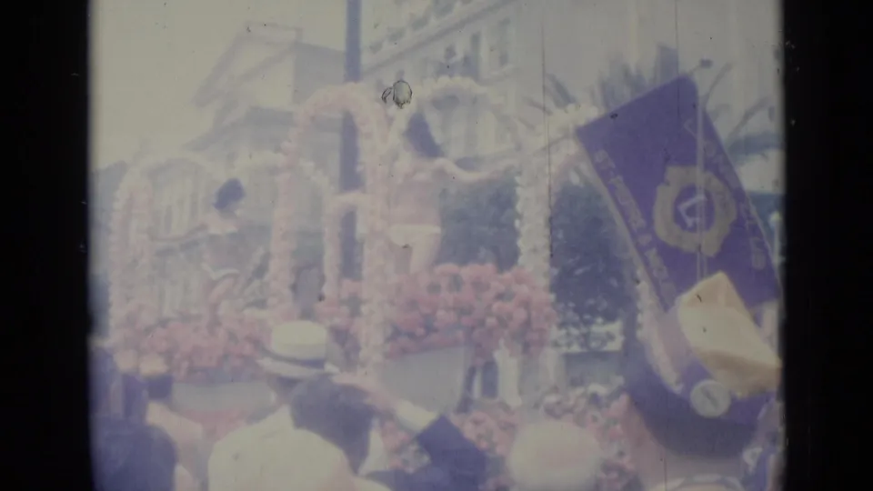 1962 Nice parade frame showing a floral-decorated float, spectators, and a purple banner along the city street.