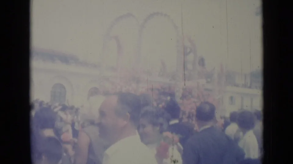 1962 Nice parade scene with spectators in the foreground and a large flower-decorated float structure moving through the street.