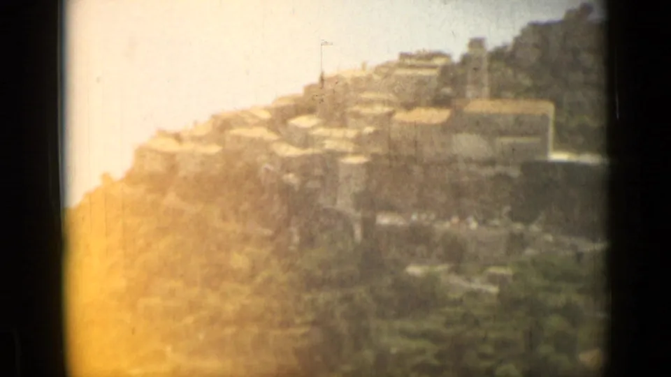 1962 Nice, France 8mm frame showing pale hillside buildings above trees, with warm overexposure and visible film borders.