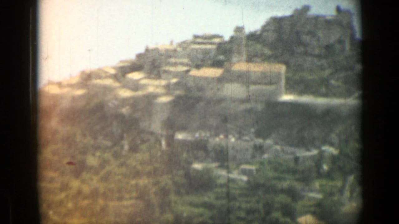 Soft 8mm frame of a hillside village with terracotta roofs and rocky slopes.