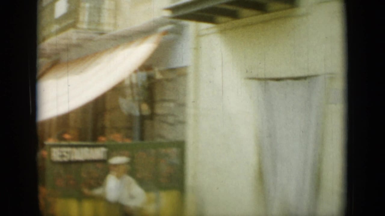 Blurred street view with awning, storefront sign, and a figure-like white shape near the curb.