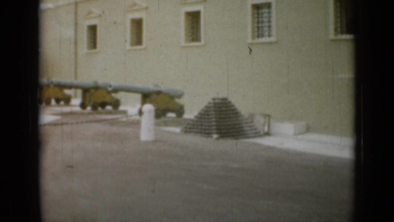 Mounted cannons, a stack of cannonballs, and a white bollard appear in a formal courtyard at the Nice, France location documented in the clip metadata.