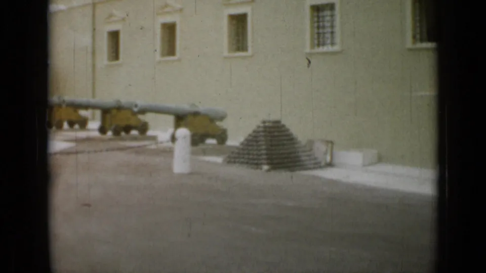 Mounted cannons, a stack of cannonballs, and a white bollard appear in a formal courtyard at the Nice, France location documented in the clip metadata.