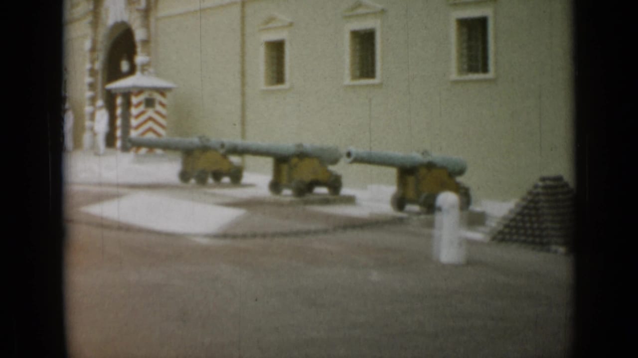 The frame shows mounted cannons, a striped guard box, and cannonballs outside a pale stone building in the 1962 Nice, France footage.