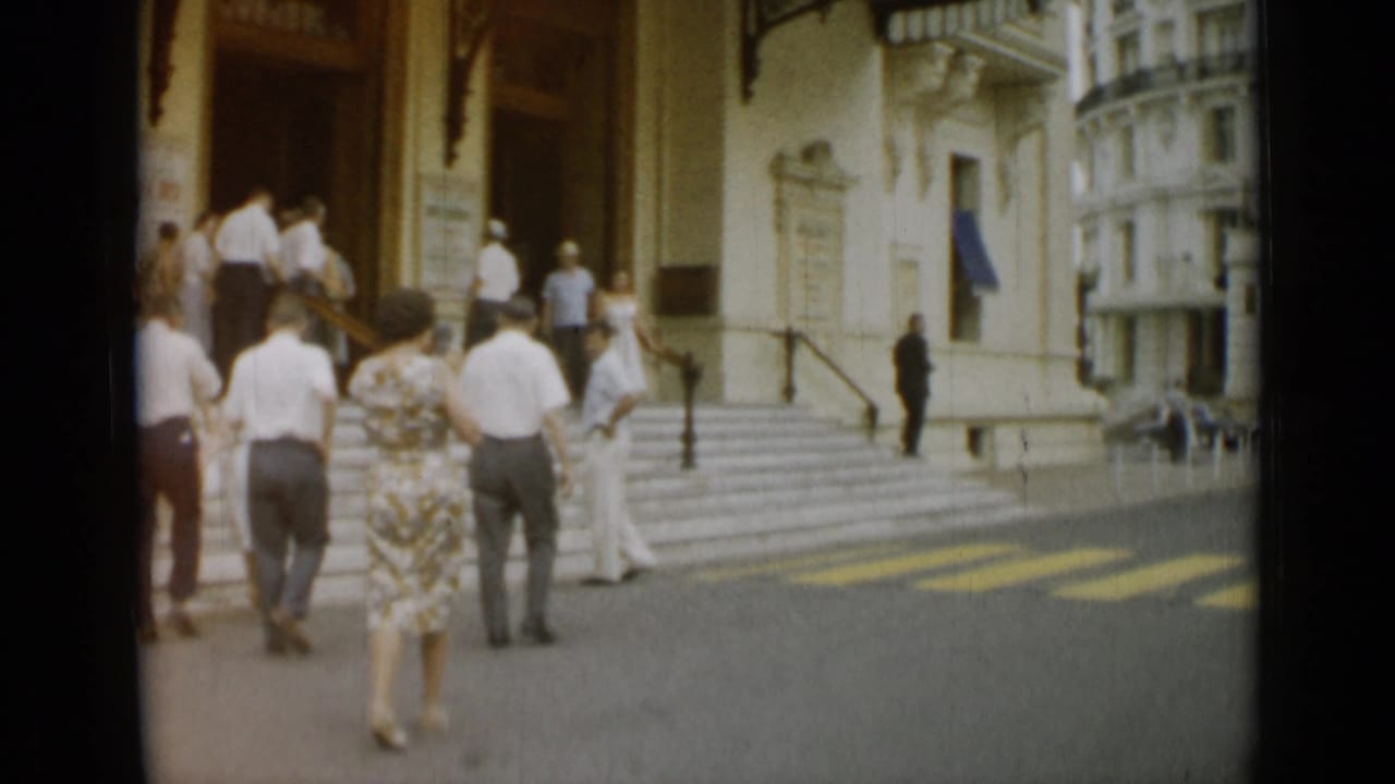 A small group of adults pauses near the steps of a grand building in Nice, France, captured in soft 8mm color.