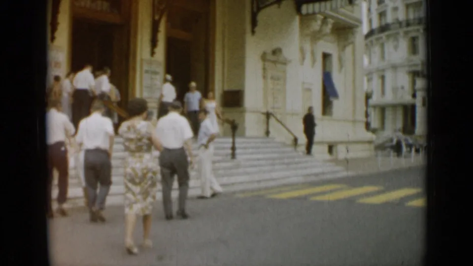 A small group of adults pauses near the steps of a grand building in Nice, France, captured in soft 8mm color.