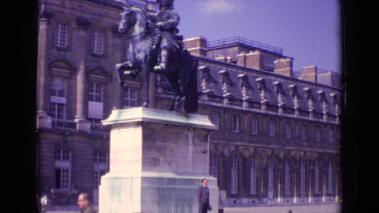1962 Paris frame with a mounted statue on a pedestal, sunlit courtyard paving, and a pedestrian moving past the historic building.