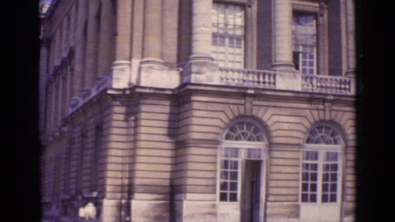 Vintage Paris frame showing a detailed palace facade with arched doorways, balcony rail, tall windows, and a small visitor figure.