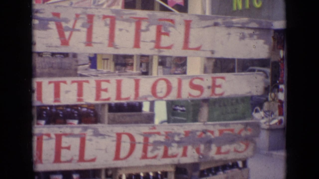 1962 Paris street detail showing stacked bottle crates with visible Vittel lettering and faded shop-sign text near storefront windows.