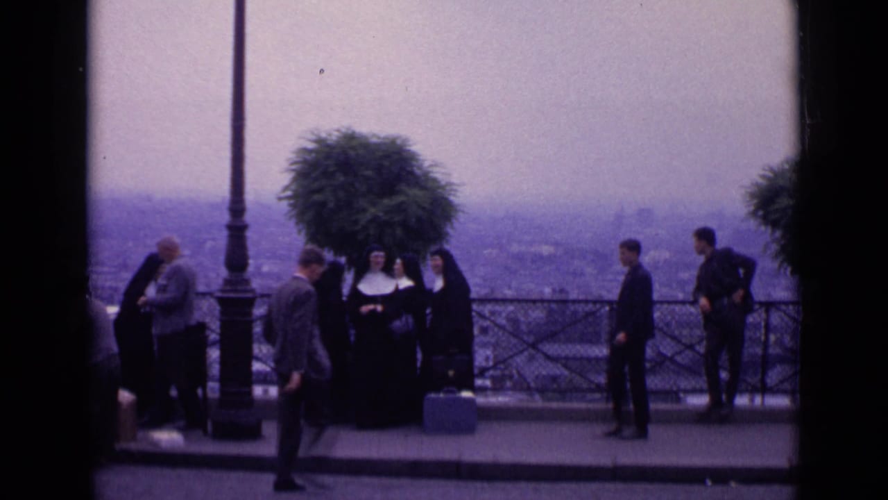1962 Paris 8mm frame with nuns in traditional habits and tourists near a lamppost at a scenic overlook above the city.