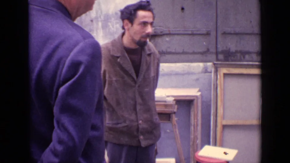 A bearded pedestrian or onlooker stands near the Paris portrait setup as the artist and easel remain partly in frame.