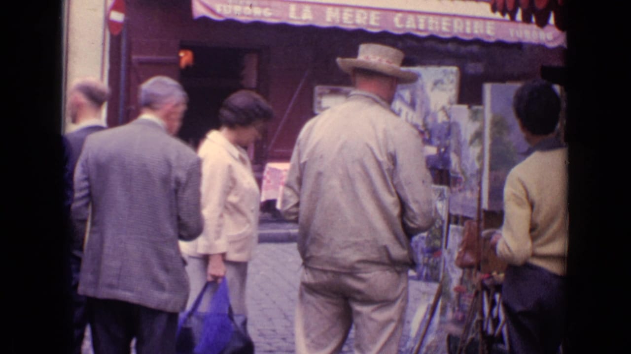 1962 Paris sidewalk scene showing people in period dress near a street artist's easels and the La Mere Catherine sign.