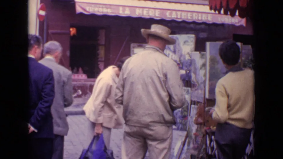 1962 Paris street footage with pedestrians clustered near an outdoor easel painter under the La Mere Catherine cafe awning.