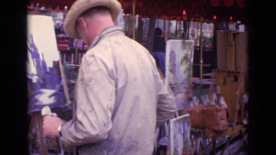 A 1962 Paris street artist in a straw hat and work jacket paints at an easel, surrounded by canvases, umbrellas, and market furniture.