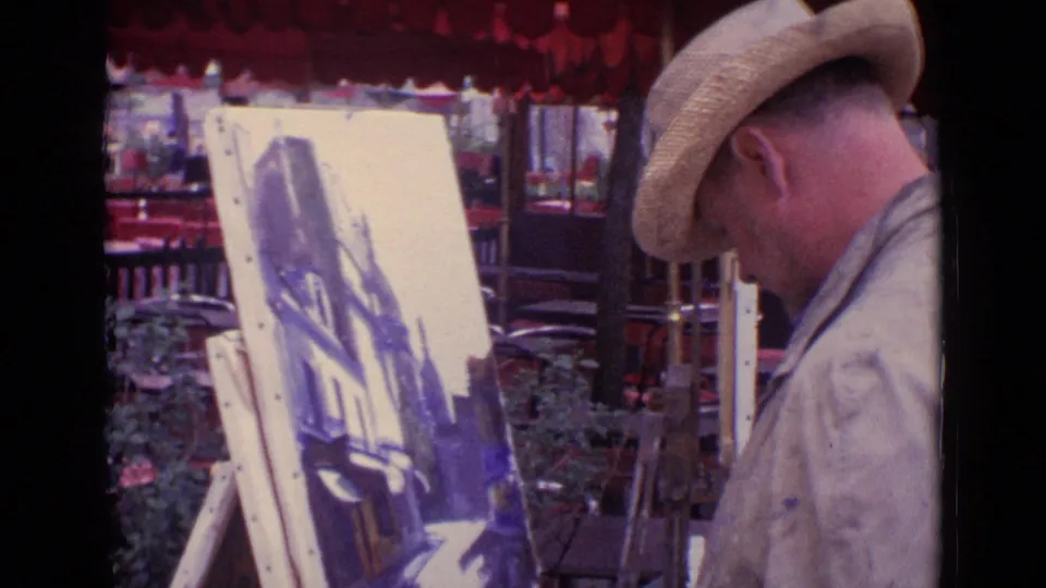 Close 1962 Paris home-movie view of a street artist in a straw hat painting a canvas beside red awnings and nearby easels.