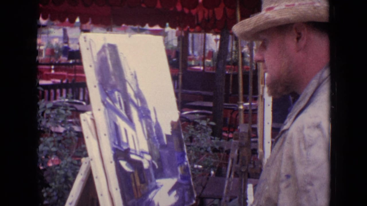 In Paris, France, 1962, a man in a straw hat stands close to a cityscape canvas under a red café awning.