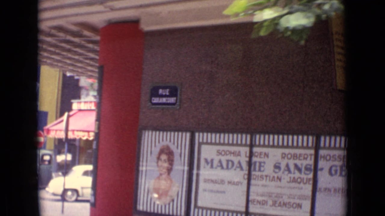 Paris street facade with a Rue Caulaincourt sign, red vertical trim, awning, and Madame Sans-Gene poster panels.
