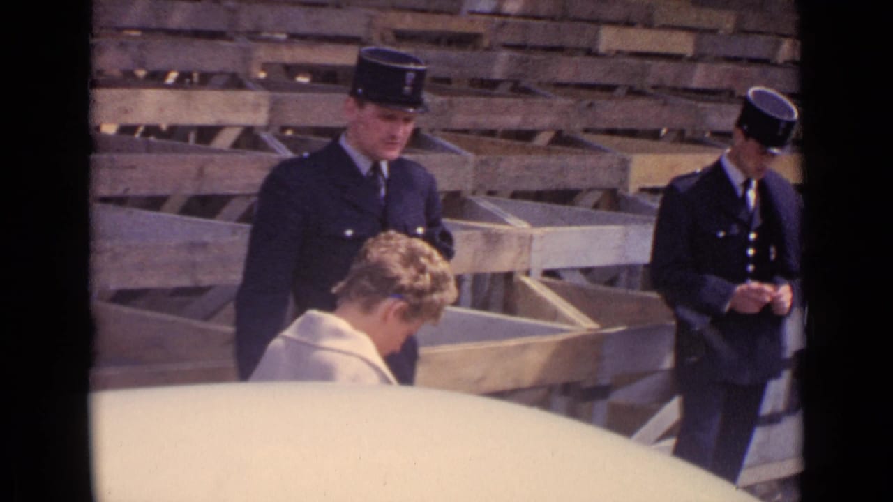 Police officers and a seated man near wooden barricades in a Paris street.