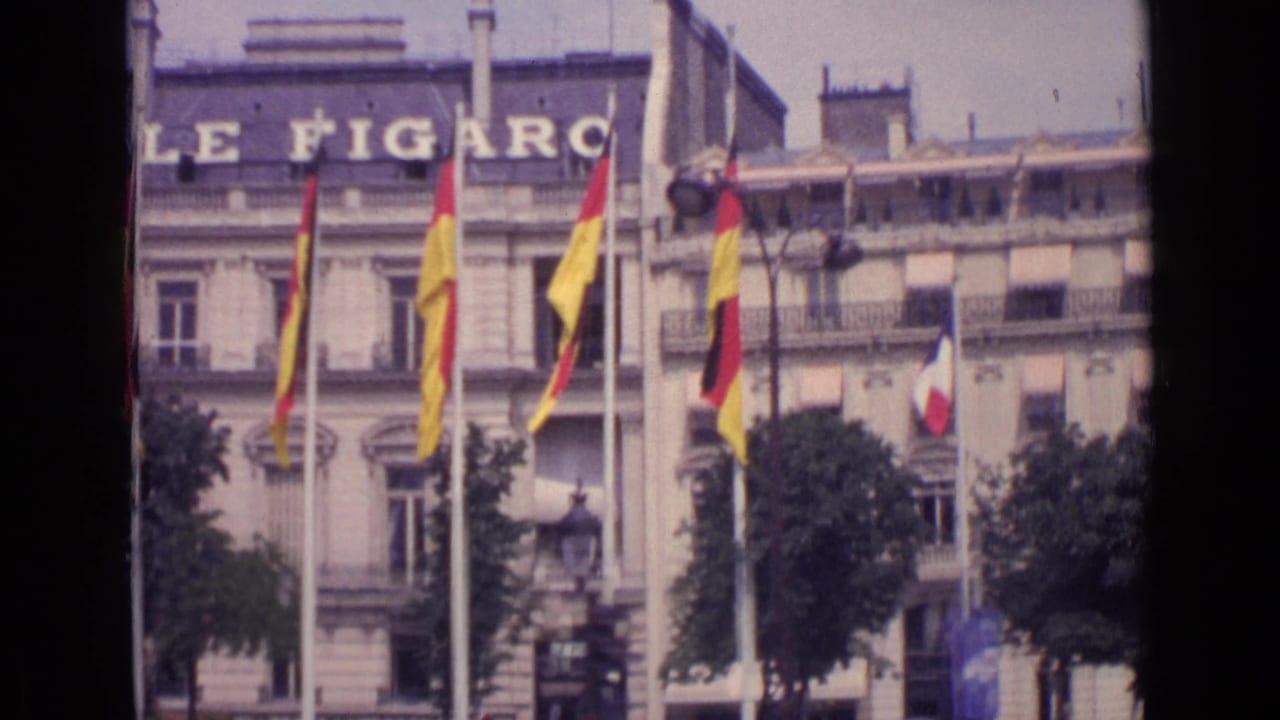 1962 Paris street view of the Le Figaro facade with French and German flags displayed on flagpoles outside.