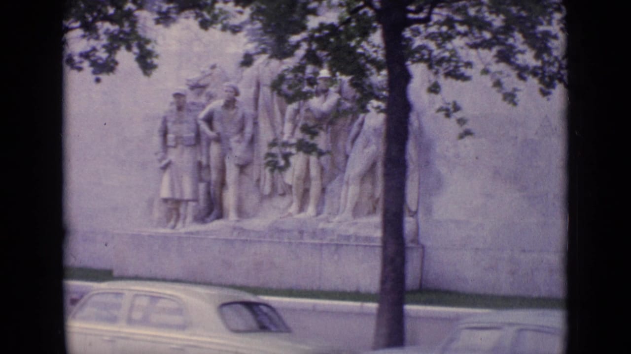 1962 Paris frame with a large stone relief on a building wall, a foreground tree, and mid-century cars near the curb.