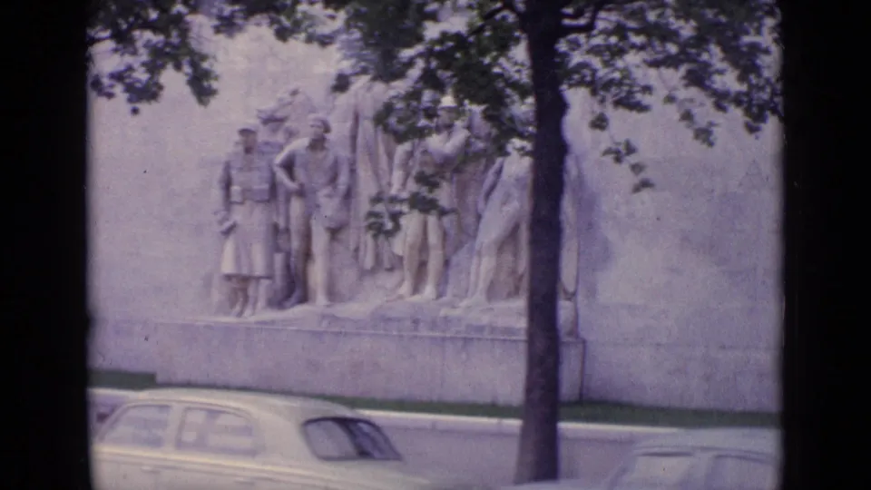 1962 Paris frame with a large stone relief on a building wall, a foreground tree, and mid-century cars near the curb.