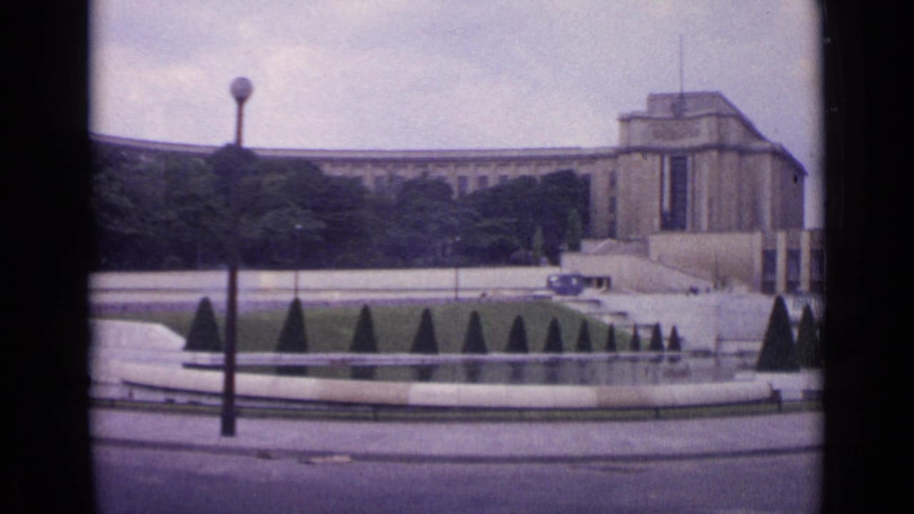 1962 Paris frame showing the Palais de Chaillot above Trocadero gardens, with a fountain basin, clipped topiary, and a tall streetlamp in view.