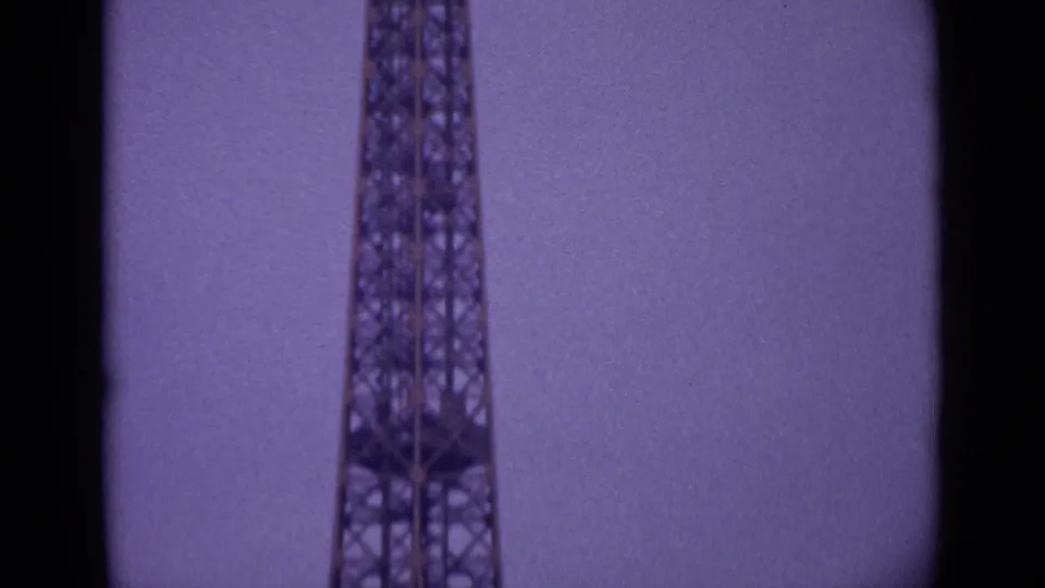 Mid-pan 1962 Paris frame showing the Eiffel Tower's iron framework, cropped tightly with visible film gate borders.