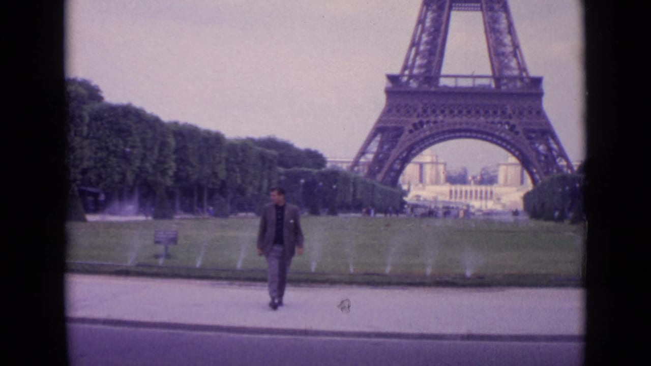 Man walking on a path in front of the Eiffel Tower and park fountains.