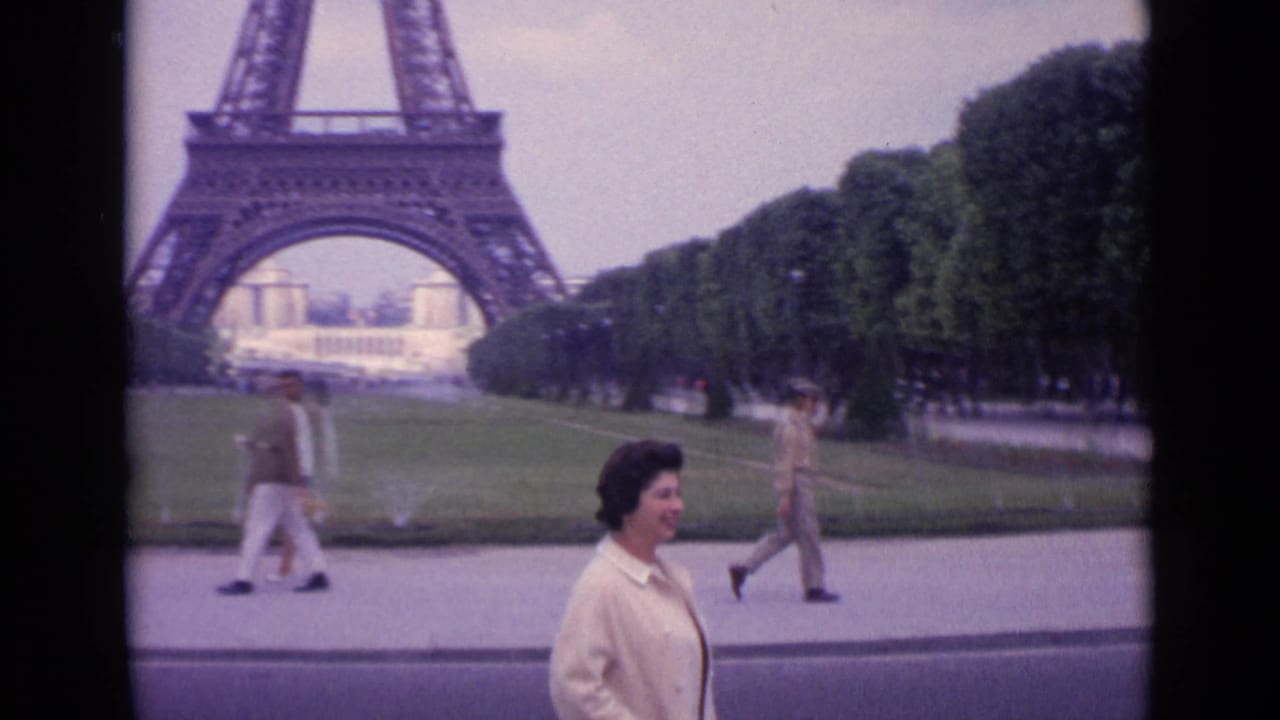 Woman walking on a path with the Eiffel Tower and lawns behind her.