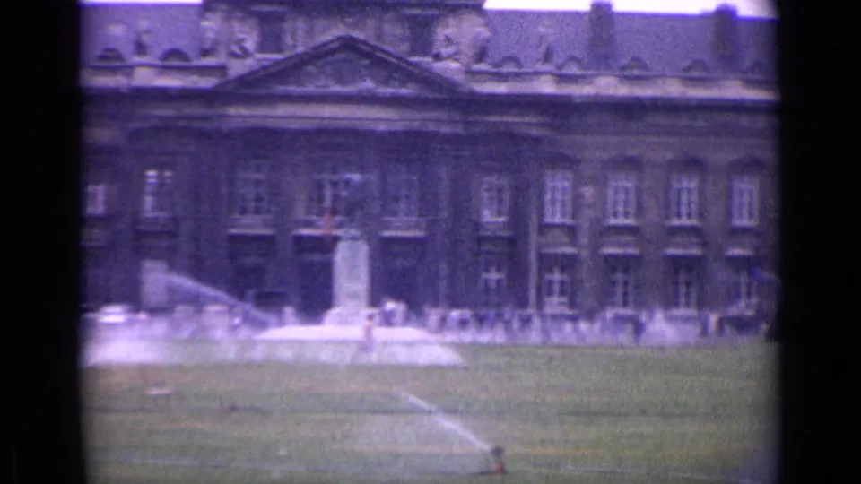 The final frame shows a Paris palace facade beyond a green lawn, with fountain spray and a foreground sprinkler caught on vintage 8mm film.