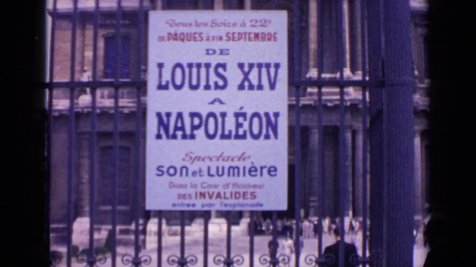 The Invalides event poster remains framed by the gate, with small figures and architectural details visible beyond it.