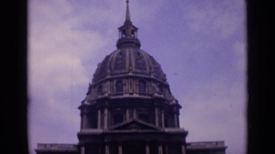 Home-movie view of the Invalides dome in Paris, softly focused with 8mm color grain and dark edge framing.