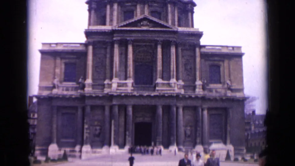 1962 Paris frame showing a monumental columned facade with a few visitors gathered near the central entrance.