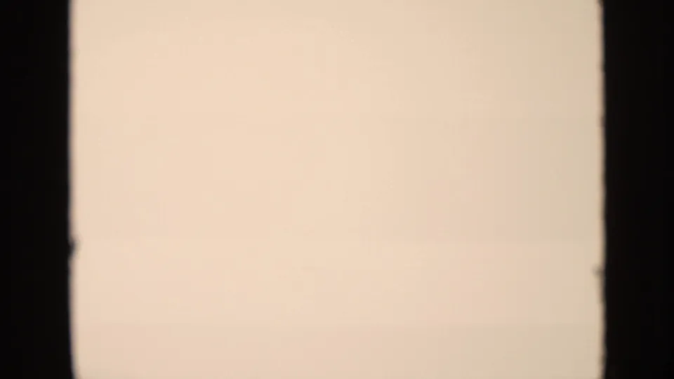End frame from the 8mm clip, mostly blank and overexposed with a warm film tint and a dark vertical gate edge.