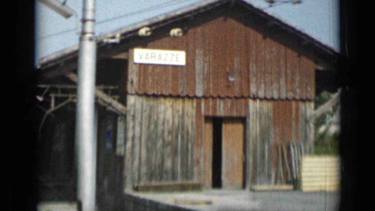 Weathered wooden station shed with a VARAZZE sign and utility poles.