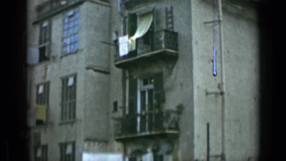 1962 Rome apartment facade with balconies, open windows, laundry, and muted 8mm color.