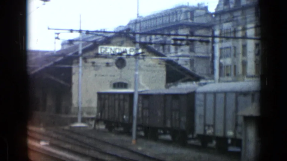 1962 Italian railway scene with freight cars, tracks, overhead lines, and a depot sign reading GENOVA B.