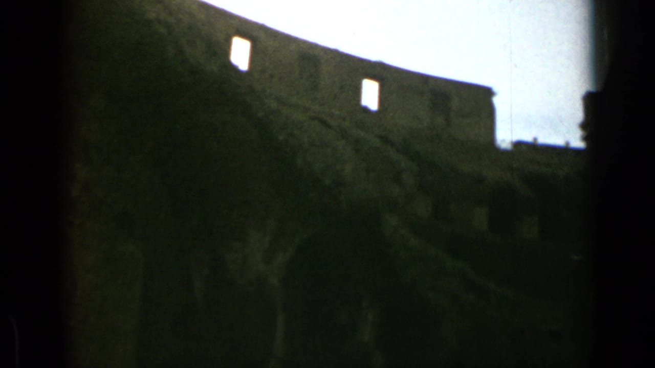 Dark handheld view of upper Colosseum walls and open sky.