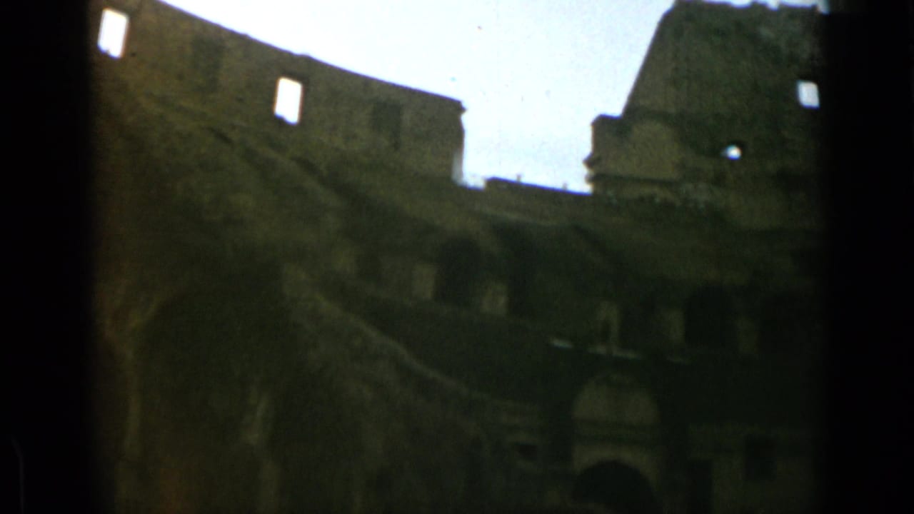 Rome Colosseum interior view on 8mm film, with dark arches below and broken stonework above.
