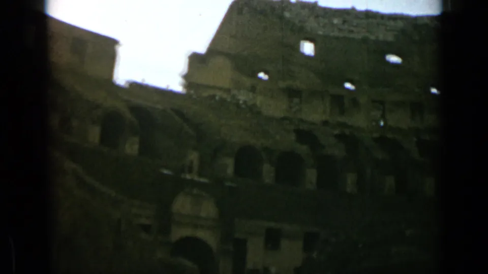 1962 visitor-shot 8mm frame of the Colosseum interior, showing arches, stone tiers, and open sky.